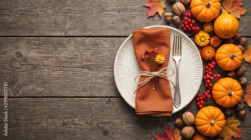 Thanksgiving table setting photo with pumpkins, autumn leaves, and plate on wooden background
