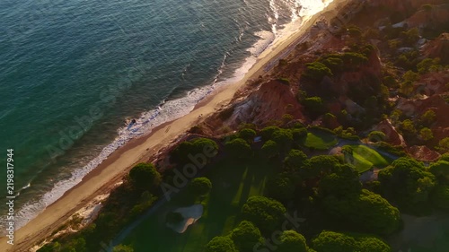 Falesia Beach, Algarve, Portugal. Golden mile beach with orange rocks, golden sand and turquoise sea. Aerial drone top view perspective. Sunset