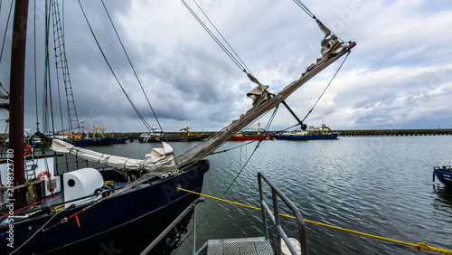 Traditional Dutch sailing ships and boats moored at a harbor dock in the Netherlands.