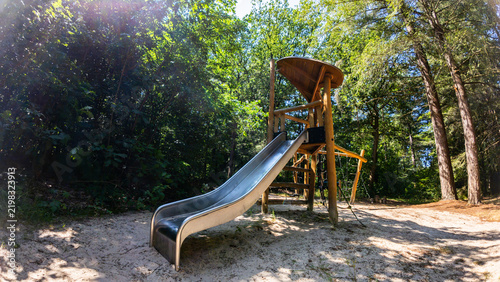 A wooden playground structure with a slide located in a forest park or recreational area in Norg, Netherlands.