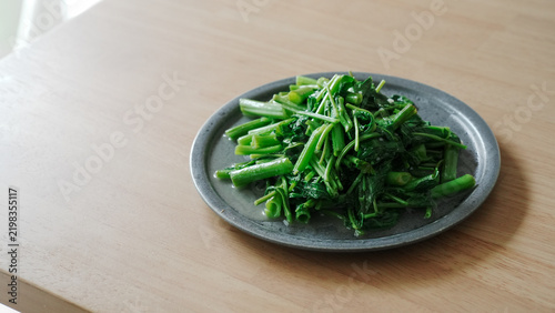 Close up of stir fried water spinach on a gray plate