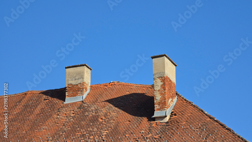 Canvastavla Weathered terracotta tiled roof with two deteriorating brick chimneys under a cl