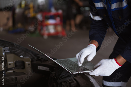 Male auto mechanic using laptop computer to diagnose car engine system