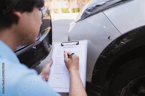 Insurance surveyor checking car damage with clipboard document site