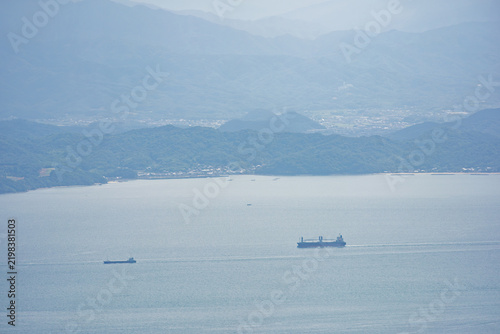 Cargo ships sail near coastal towns and mountains