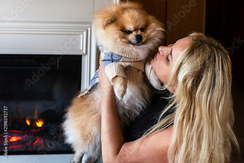 Woman Cuddling Pomeranian Dog Near Fireplace