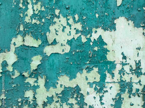 Peeling turquoise paint on an old weathered wall. 