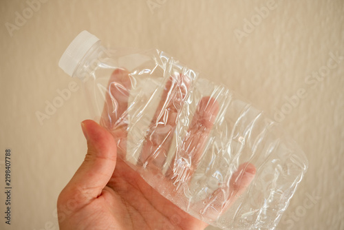 фотографія Hand crushing a plastic bottle, preparing for recycling and promoting environmen