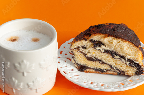 White mug of coffee and poppy seed cake on a white plate