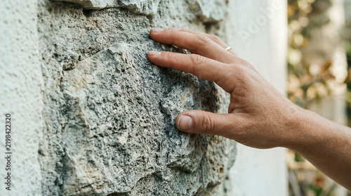Close-Up of Person Touching Rough Stone Wall Outdoors