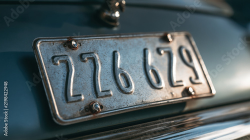 Vintage metal license plate with embossed characters on classic car body — macro car detail  