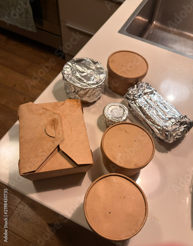 Various food delivery containers sit on a kitchen counter near a sink showcasing a quick meal option for later use.