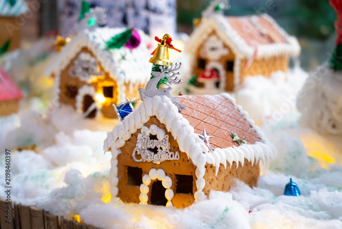 Festive Christmas miniature village with decorated gingerbread houses, cotton snow, tiny trees, ornaments, and warm glowing lights for holiday home decor. made by kids at home