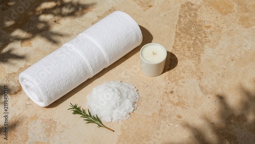 Spa Setup With Towel, Salt, Candle, and Rosemary on Stone Surface