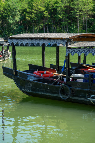 фотографія Traditional Chinese wooden pleasure boats on a green lake water, scenic park bac