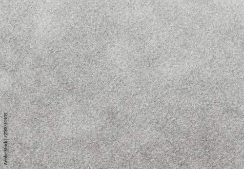 Fleecy mottling in gray felt with dense tangled fibers gathered into irregular patches, a nonwoven textile background with short loose strands and uneven shading through the fuzzy material