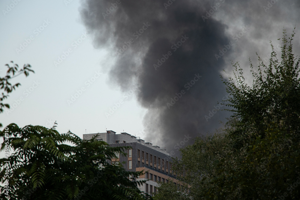 Obraz premium Thick black smoke rises from the top of an apartment building after a drone attack in Ukraine. The concept of fire, missile attack, drone raid