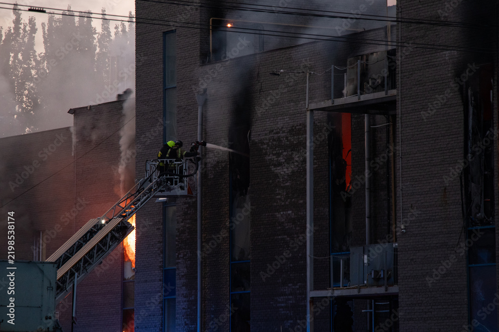 Obraz premium Firefighters put out the burning building of the shopping center. Smoke and fire after a drone attack in Ukraine, rescuers are working at the scene