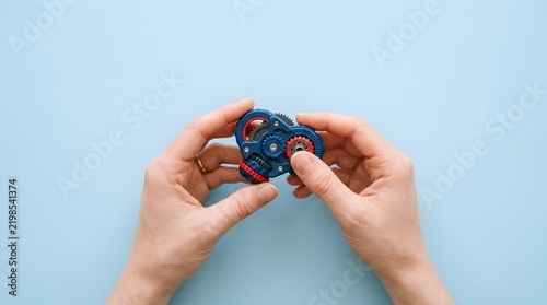 Top view of hands holding a small blue electronic microcontroller board isolated on a light blue background