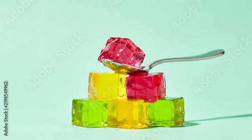 Jelly cubes stacked on a table with a spoon resting nearby