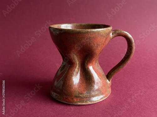 Hourglass shaped ceramic coffee mug on pink background