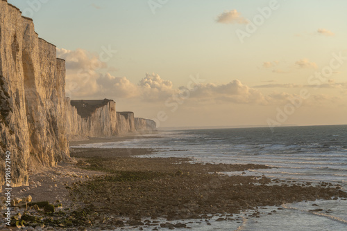 Obraz na plátne Sunset over chalk cliffs by the sea creating shadows and reflections on a calm b