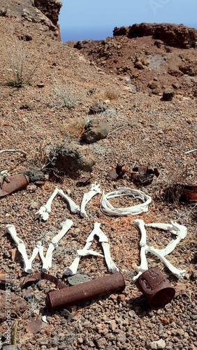 Bones forming the phrase No War on dry, rocky terrain with scattered rusted metal pieces, symbolizing peace, the devastating consequences of conflict, and the urgent need to stop wars