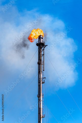 Oil refinery flare stack with a huge flame burning gas