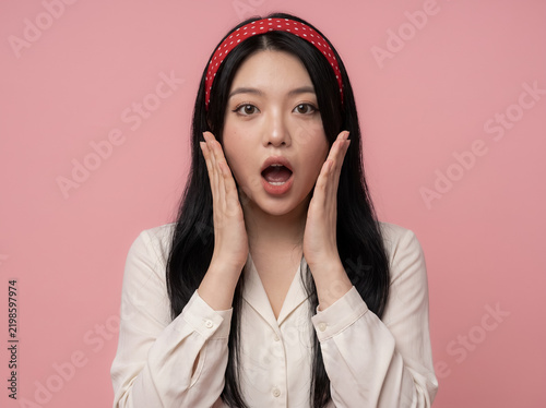 Foto Shocked woman holding cheeks on pink background