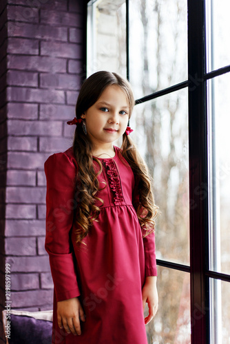 Three-Quarter Portrait of Young Girl in Red Dress Standing by Window