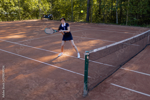 Bild auf Leinwand Two-handed backhand in tennis, woman meets the ball on a clay court, stroke technique