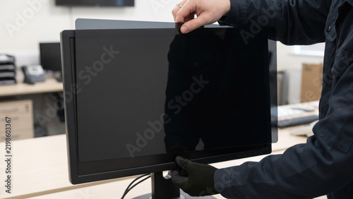 Technician Attaching Privacy Filter to Workstation Monitor for Security