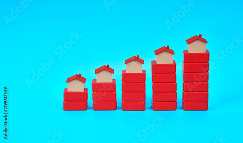 Cuadro en lienzo Miniature houses placed on ascending stacked blocks represent rising property values and housing market growth