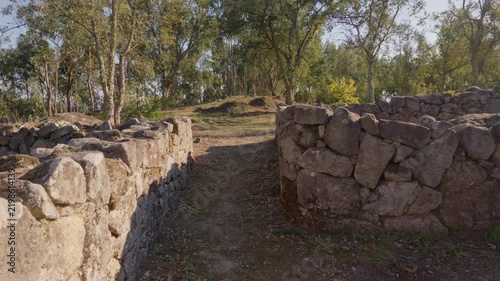 Ancient stone walls of the archaeological site of Castro de Romariz in Portugal under a warm sunny sky.