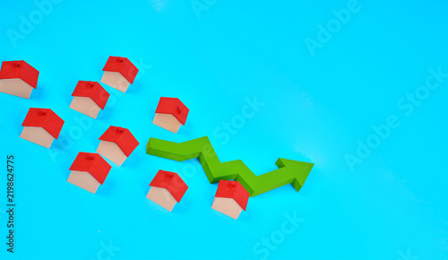 Fotografía Miniature houses beside an upward arrow represent rising property values and growth in the real estate market