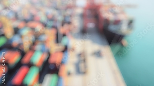 A blurred image of a busy shipping port with colorful containers stacked on cargo ships, showcasing the logistics and maritime industry.