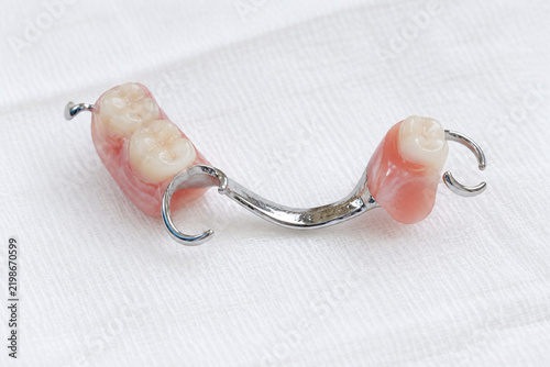 Partial denture with metal clasps on white cloth, partials dental care and prosthesis concept