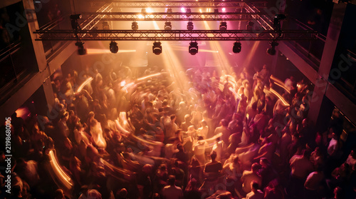 Nightclub crowd dancing with glowing stage lights overhead and motion blur