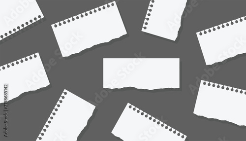 Scattered torn notebook paper sheets with binder holes arranged on a dark grey background for creative note taking or designs.
