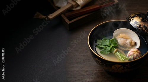 Steaming Japanese clear clam soup with temari fu and mitsuba in gold maki-e lacquer bowl with copy space