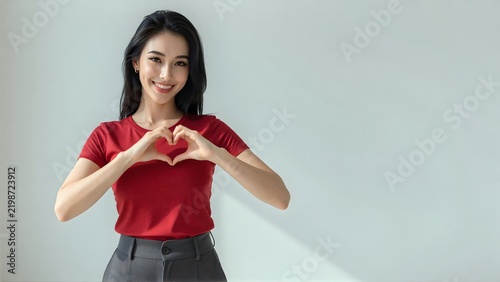 Beautiful young Asian woman making a heart sign with hands