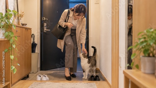 Plakat 帰宅した女性を玄関で迎える猫