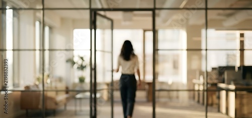 Business woman walking through glass door in modern bright office