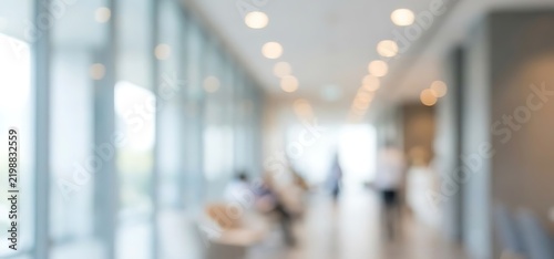 Blurred interior of a modern office building hallway with glass windows and glowing ceiling lights