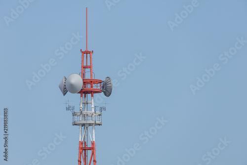 Obraz na plátně Upper section of a red-and-white communication tower featuring parabolic dish antennas, stacked circular ring platforms, directional Yagi arrays, and dipole antennas against a clear blue sky