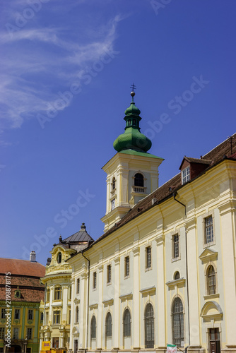 Fotografie The historic Sibiu Lutheran Cathedral tower and adjacent buildings under a clear blue sky
