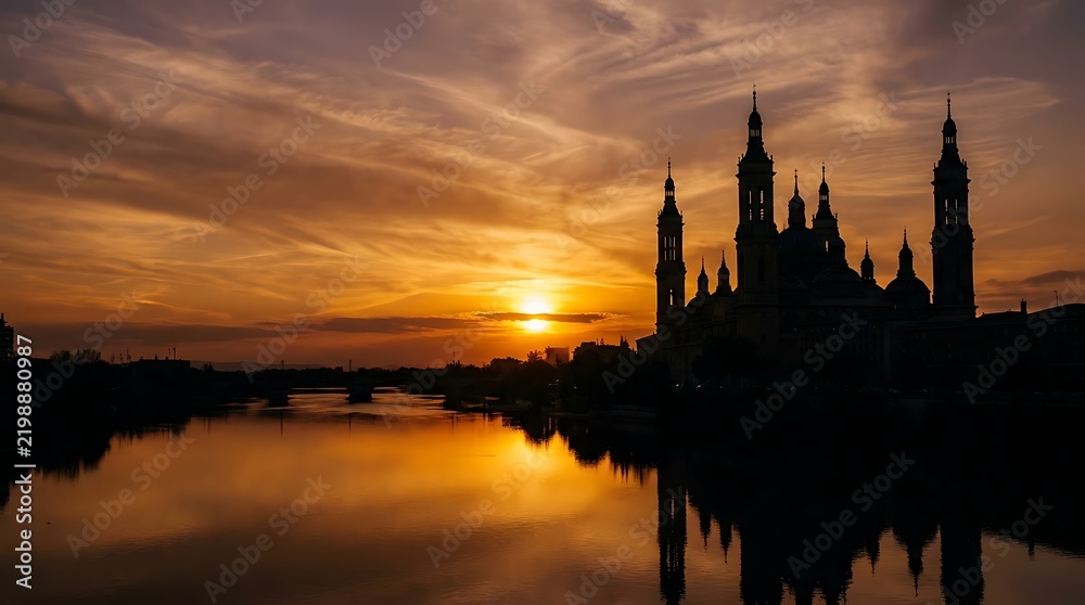 Naklejka premium Stunning golden sunset over the historic basilica reflected in the tranquil river water of a beautiful european city