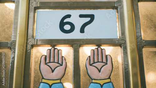 Number 67 sign displayed above decorative stained glass window panels