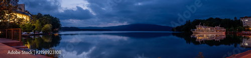Panoramic view of Lake Akan at blue hour in Akankohan, Hokkaido, Japan, with mountains, lakeside buildings, boats, and reflections on the water.