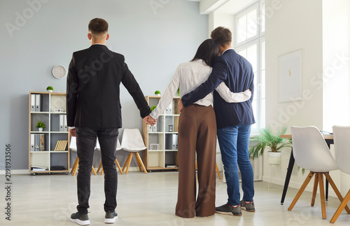 Foto Back view in a bright office: a woman hugs her lover while secretly holding another man's hand, symbolizing infidelity, cheating, and deception